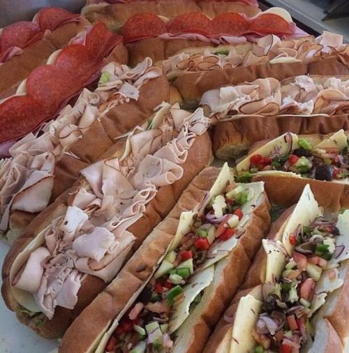 A variety of sandwiches with different meats, cheeses, and fresh vegetables arranged on a platter.