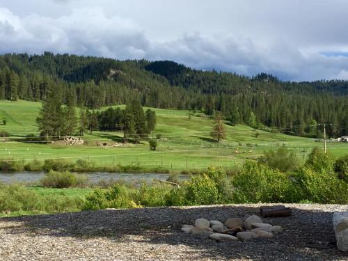 A scenic landscape featuring green hills, trees, and a river under a partly cloudy sky.