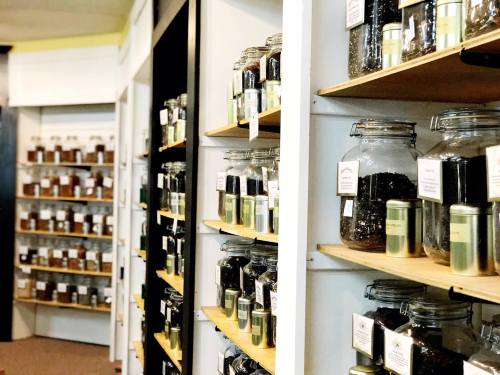 A cozy shop interior with shelves filled with jars and tins of various herbs and spices.
