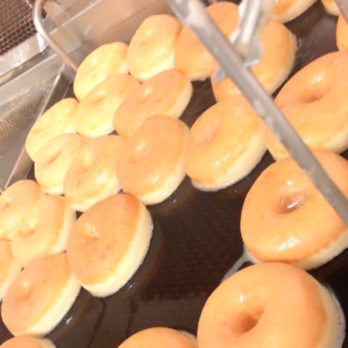 Freshly fried donuts cooling on a rack, golden brown with a glossy glaze.