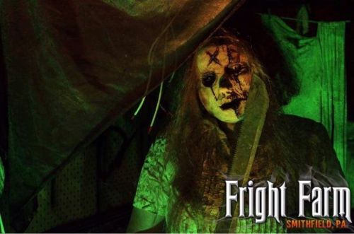 A creepy figure with a mask and a knife stands in a dimly lit, eerie setting, promoting Fright Farm in Smithfield, PA.