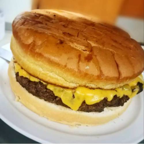 A large cheeseburger with melted cheese on a toasted bun, served on a white plate.