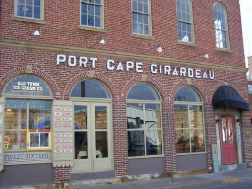 Brick building with "Port Cape Girardeau" sign, featuring large windows and an ice cream shop display.
