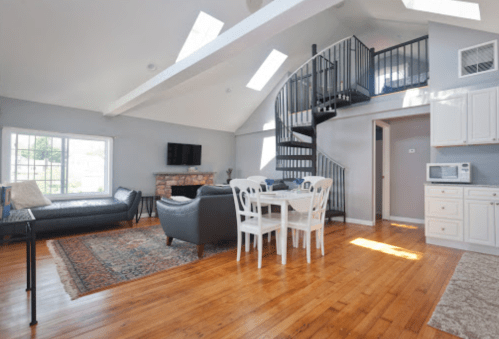 Bright, modern living space with a spiral staircase, dining area, and large windows showcasing natural light.