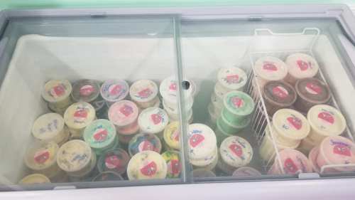 A freezer filled with various containers of ice cream, each labeled with colorful stickers.