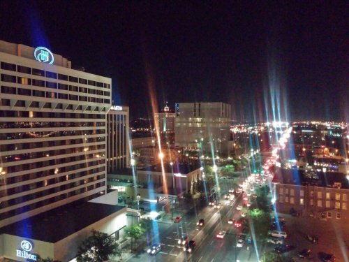 City skyline at night, featuring illuminated buildings and busy streets under a clear sky.