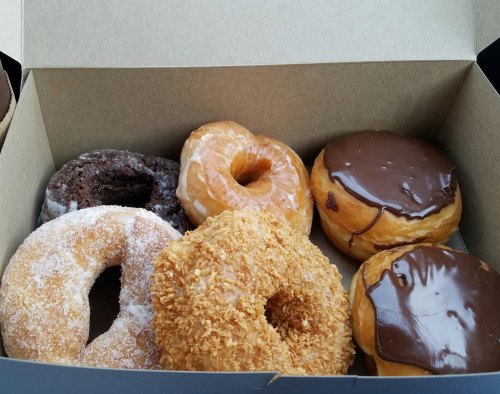 A box of assorted donuts, including chocolate, glazed, and coconut-covered varieties.