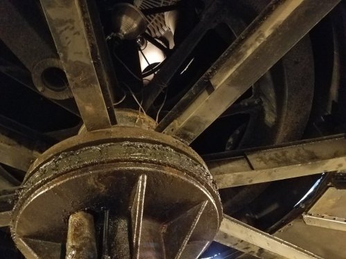 Close-up of a large, industrial fan's metal blades and central hub, showing signs of wear and grease.