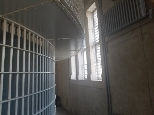 Interior view of a building featuring a curved metal structure and windows with horizontal slats.