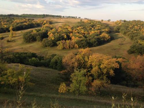 A scenic landscape featuring rolling hills and trees in vibrant autumn colors under a partly cloudy sky.