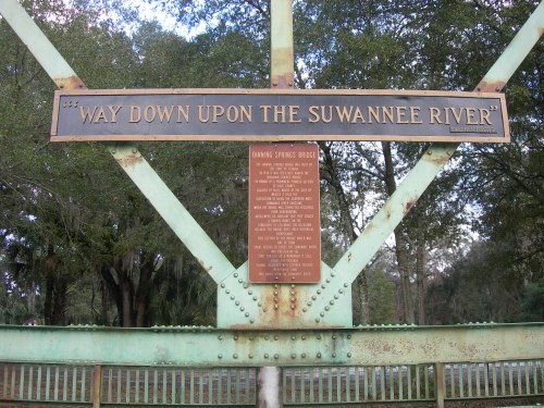 Sign on a bridge reading "Way Down Upon the Suwannee River," with a plaque detailing the song's history.