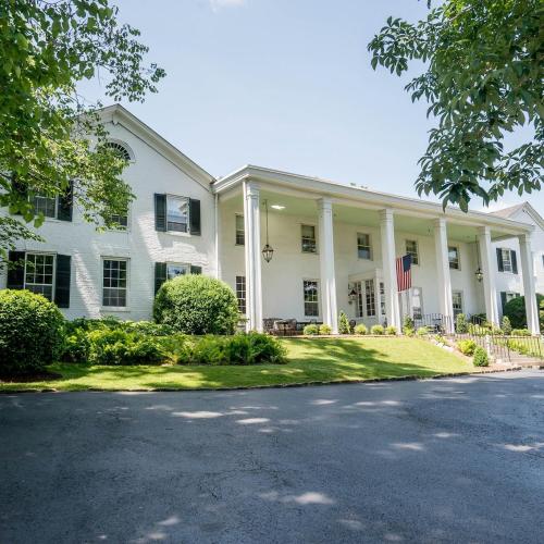 A large white house with columns, an American flag, and a well-maintained lawn under a clear blue sky.