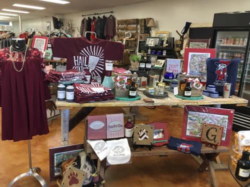 A display of merchandise including clothing, candles, and decor items in a cozy shop setting.