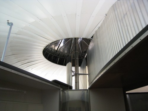 Interior view of a modern building featuring a circular skylight and curved ceiling panels.