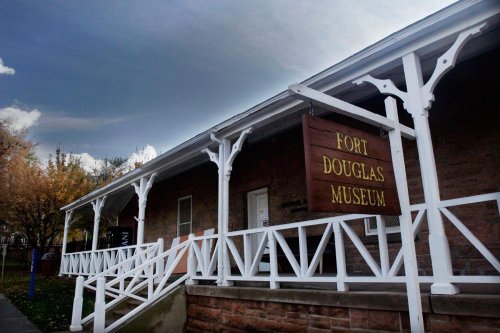 Exterior view of the Fort Douglas Museum, featuring a wooden sign and white railings against a cloudy sky.
