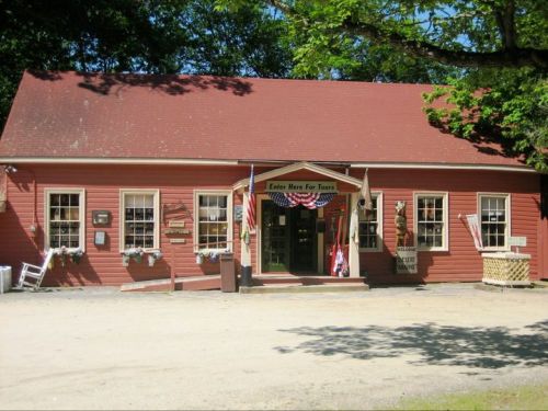 A charming red building with a sloped roof, featuring a welcoming entrance and decorative flags.