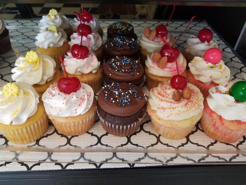 A display of colorful cupcakes with frosting, sprinkles, and cherries on top, arranged neatly on a tray.