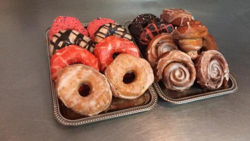 A tray of assorted donuts, including glazed, frosted, and cinnamon rolls, in various colors and designs.
