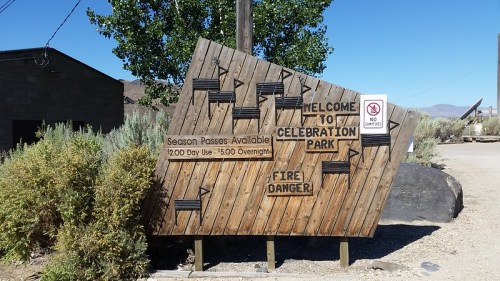 Wooden sign at Celebration Park, noting season passes, day use hours, and fire danger warnings.