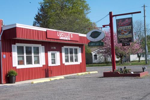 A red building with a sign reading "Lucille's Country Cooking," surrounded by trees and a gravel parking area.