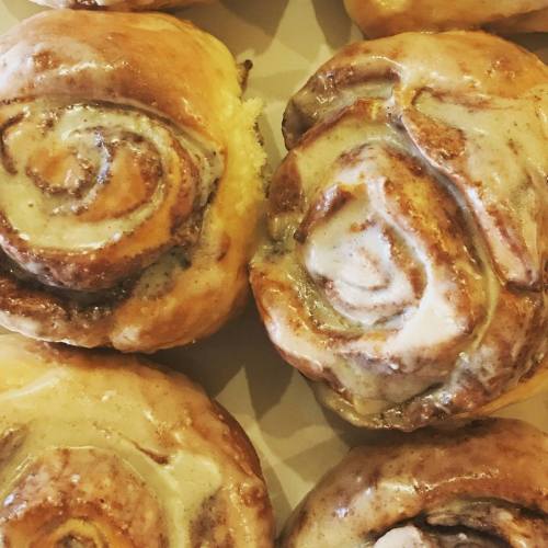 Close-up of freshly baked cinnamon rolls with creamy icing, showcasing their swirled texture and golden-brown color.