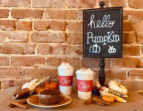 A cozy fall display with two coffee cups, a chocolate dessert, pumpkins, and a chalkboard sign saying "hello Pumpkin."