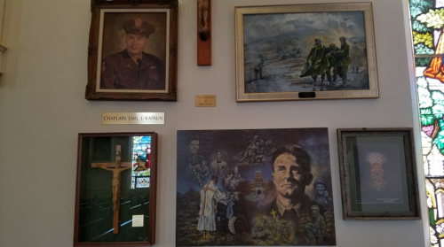 A wall display featuring portraits and artwork, including a military chaplain and historical scenes.