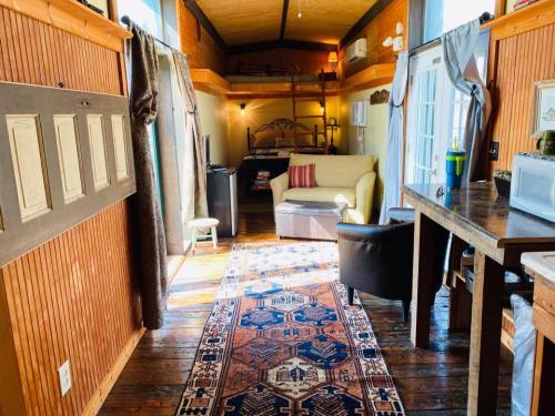 Cozy interior of a tiny home featuring a sofa, wooden floors, a rug, and a lofted sleeping area.