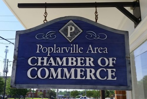 Sign for the Poplarville Area Chamber of Commerce, featuring a blue background and decorative lettering.