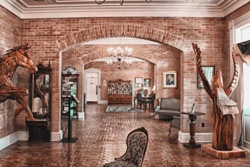A spacious room with brick walls, wooden sculptures, and elegant furniture, featuring arches and a cozy atmosphere.
