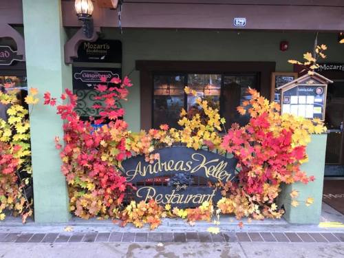 A restaurant entrance adorned with vibrant autumn leaves in shades of red, orange, and yellow.