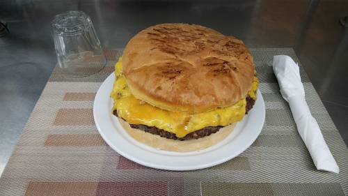 A large cheeseburger with two layers of melted cheese on a toasted bun, served on a plate with a napkin.