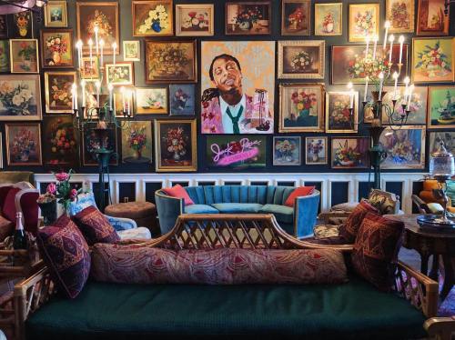 A cozy room with colorful floral artwork, a vibrant portrait, and plush seating arrangements.