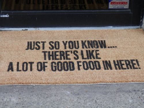 A doormat with the text: "Just so you know... there's like a lot of good food in here!" in bold black letters.
