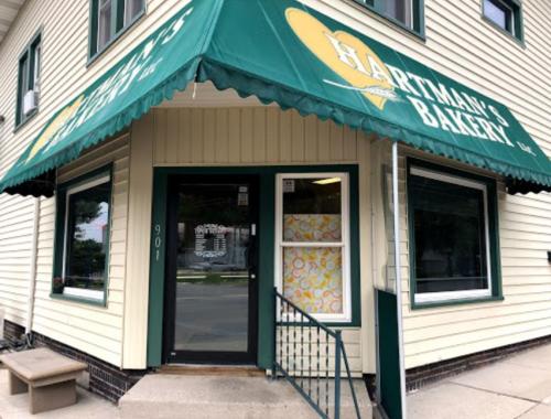 Exterior of Bartman's Bakery, featuring a green awning and large windows, with a welcoming entrance.