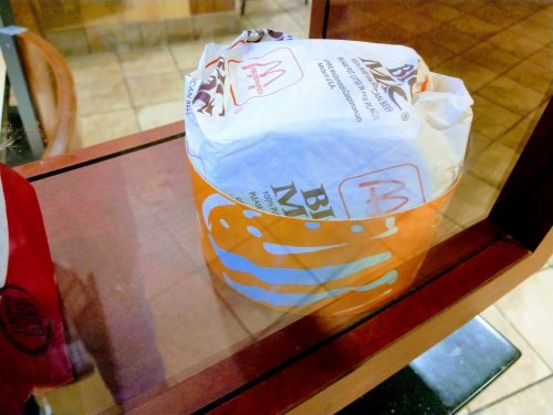 A wrapped burger in a display case, featuring McDonald's and Burger King branding.