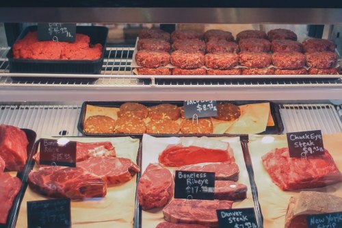 A display case filled with various cuts of meat, including steaks and ground beef, with price tags visible.