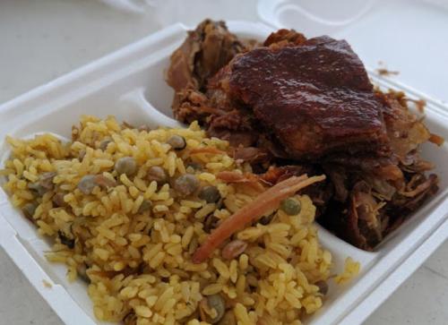A takeout container with seasoned rice and tender, shredded meat.