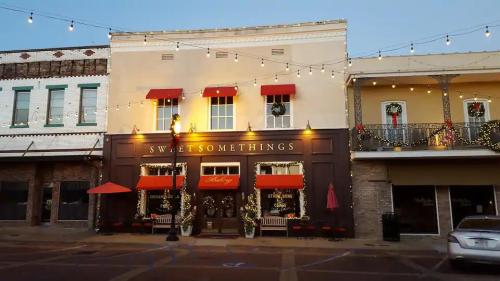 A charming storefront decorated for the holidays, featuring red awnings and string lights in a quaint town setting.
