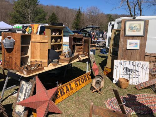 A vintage market scene featuring wooden furniture, antiques, and decorative items displayed outdoors.