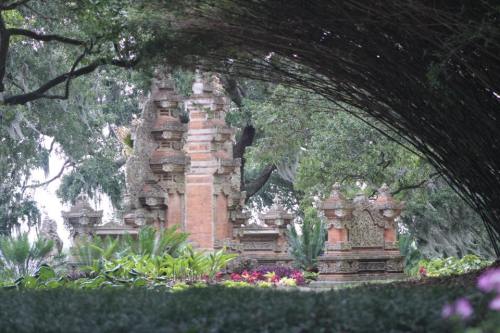 A serene garden scene featuring ornate stone structures surrounded by lush greenery and colorful flowers.
