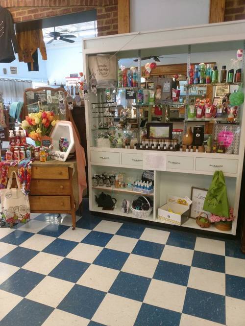A cozy shop interior featuring a display case, colorful products, and a variety of decorative items on a checkered floor.