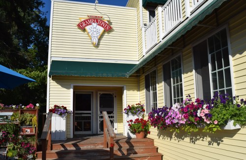 Exterior of Grampa Tony's restaurant, featuring a yellow building, welcoming entrance, and colorful flower pots.