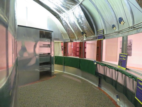 Interior of a retro-style diner with metallic walls, green accents, and a patterned carpet.