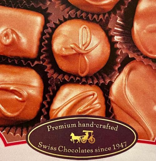 Assorted premium Swiss chocolates in a decorative box, featuring various shapes and designs.