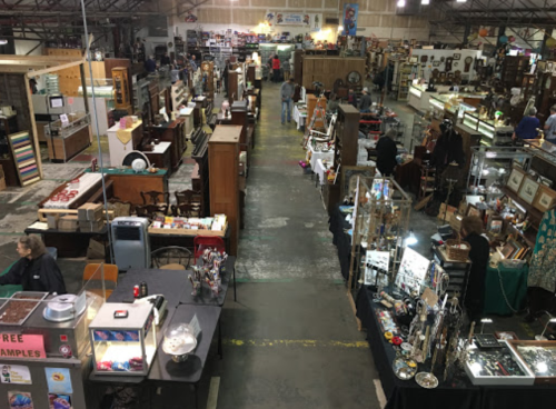 Aerial view of a bustling antique market with various booths displaying furniture, collectibles, and crafts.