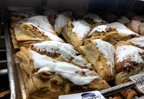A tray of flaky pastries drizzled with white icing, featuring a mix of cinnamon and fruit fillings.