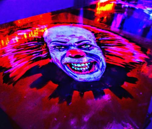 A vibrant, eerie clown face with sharp teeth and glowing colors, set against a dark background.