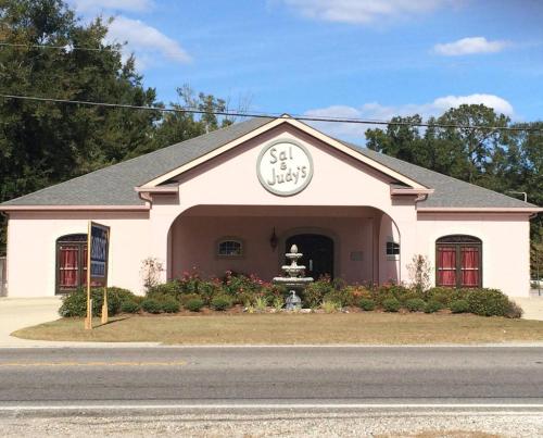 A pink building with a sign reading "Sal & Judy's," featuring a fountain and landscaped front yard.