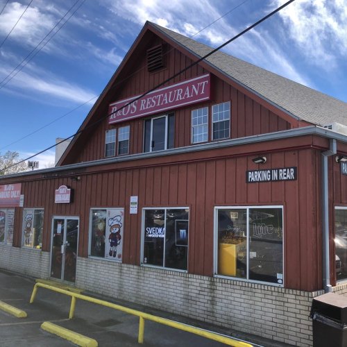 Exterior of D & US Restaurant, a red wooden building with a sign, featuring parking instructions and colorful window displays.